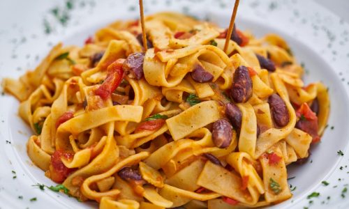 Close-up of delicious Italian pasta dish with kidney beans and rich sauce.