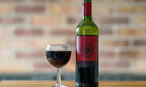 Elegant presentation of a Cabernet Sauvignon bottle and glass on a wooden table.