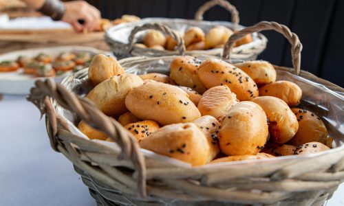 Close-up of freshly baked bread rolls with poppy seeds in woven wicker baskets, perfect for a bakery setting.